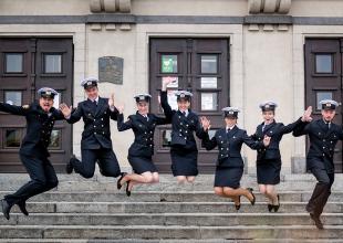 Studenci UMG przed frontonem budynku zeskakujący ze schodów